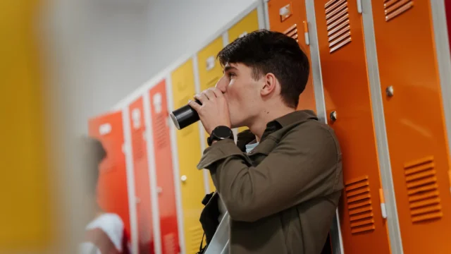 teen-student-drinking-energy-drink-in-school-hallway.webp.webp