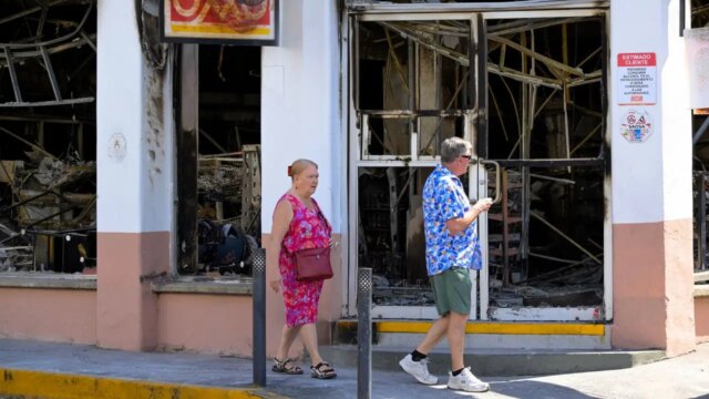 tourists-walk-past-a-burned-shop.jpg