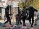 Momento aterrorizante, homens encapuzados atacam uns aos outros com facões no centro da cidade enquanto espectadores aterrorizados e batalha policial