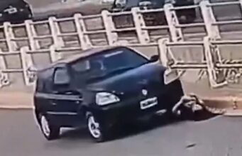 No momento em que uma mulher verifica a bateria do carro, o próprio motor atropela após conectar o cabo auxiliar