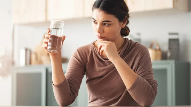 worried-woman-examines-glass-of-drinking-water.webp.webp