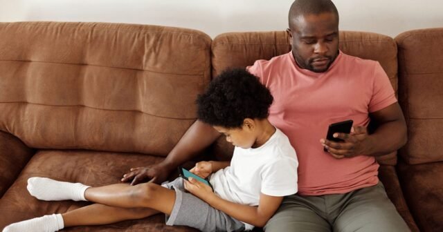 Father-and-son-bonding-over-smartphones-while-relaxing-on-a-comfortable-couch-at-home.jpg