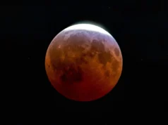 Um eclipse lunar parcial surpreende os observadores do céu com uma “lua quase sangrenta”. Aqui estão as melhores fotos A full moon is photographed in a black sky with its upper left portion shadowed during a lunar eclipse.