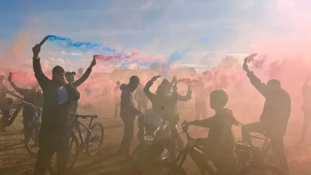 Jovens mascarados soltam fogos de artifício e soltam balões em antecipação aos passageiros do A66.