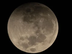 O que esperar de cada fase do eclipse lunar parcial de 27 e 28 de agosto A full moon is shown in a black sky with its upper edge shadowed during a partial lunar eclipse.