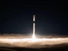 SpaceX envia 27 satélites Starlink em órbita no 100º lançamento do foguete Falcon do ano (vídeo, fotos) a stack of folded-up satellites are seen attached to their rocket's upper stage in orbit, with earth in the background