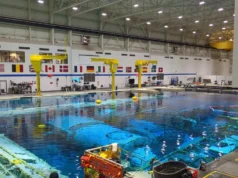 Como o Centro de Treinamento de Astronautas da NASA mudará com as estações espaciais comerciais? a large swimming pool inside a hangar-like building